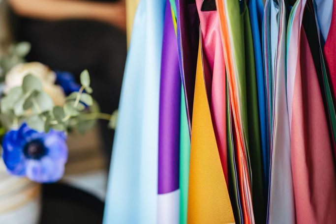 Bunte Stoffe hängen neben einer blauen Blume in einer Vase.